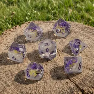 Set di sette dadi Mooncap in resina trasparente con numeri viola e piccoli funghi viola inclusi, su un ceppo d'albero