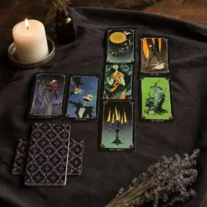 Carte dei Tarocchi Nightmare Before Christmas su panno scuro, dorsi a motivi viola, candela accesa e lavanda