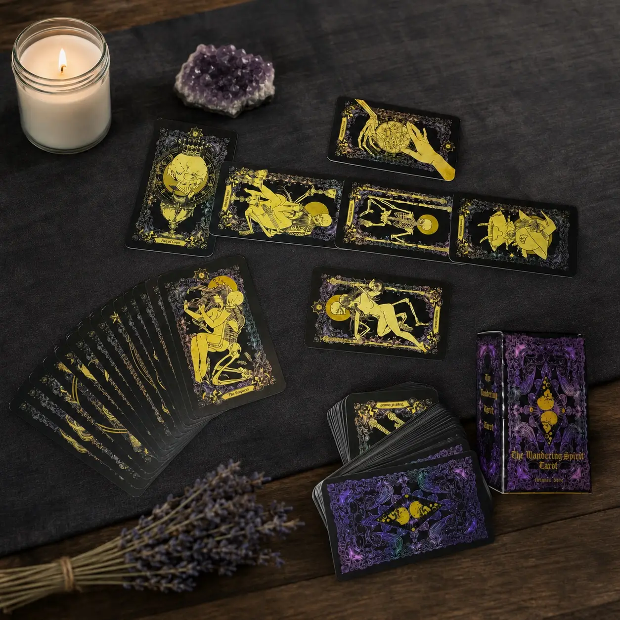 The Wandering Tarot deck with black and gold skeleton cards spread out, purple box, candle, amethyst and lavender